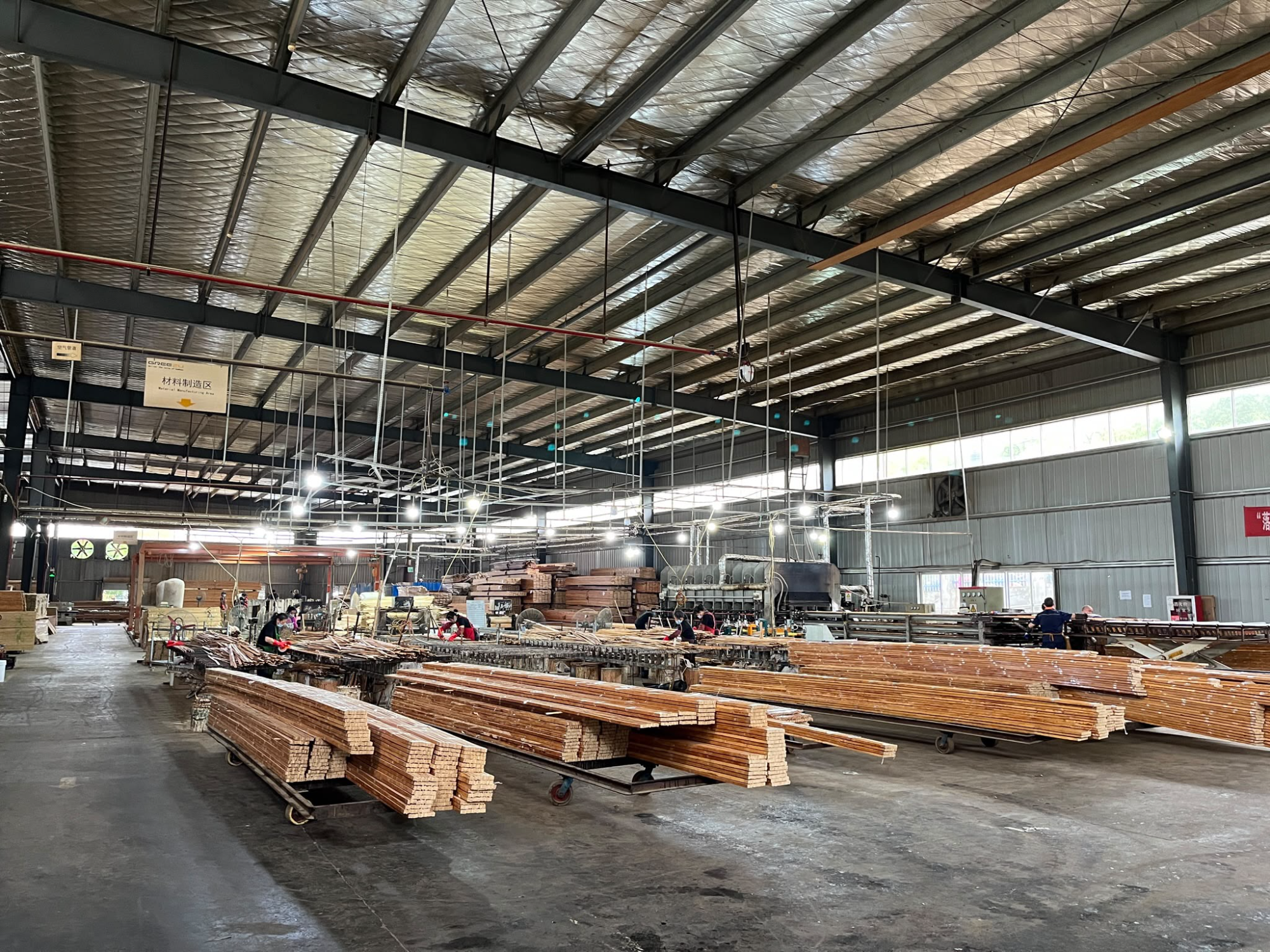An industrial bamboo processing line with machinery and long bamboo members being prepared